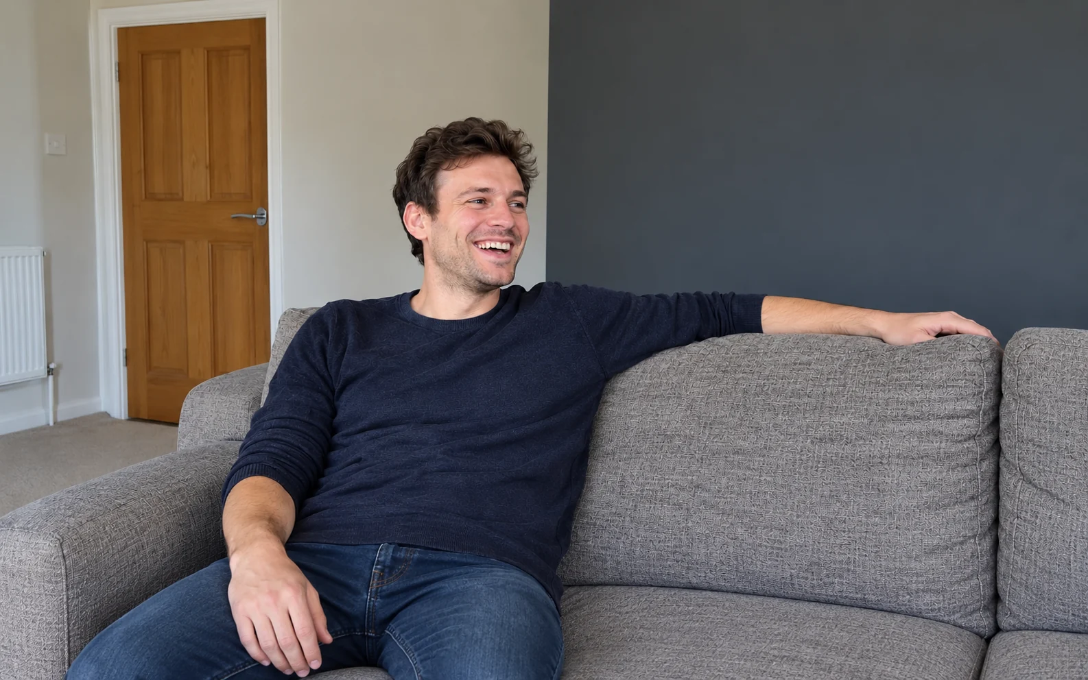 A man laughing on a sofa at home in the afternoon