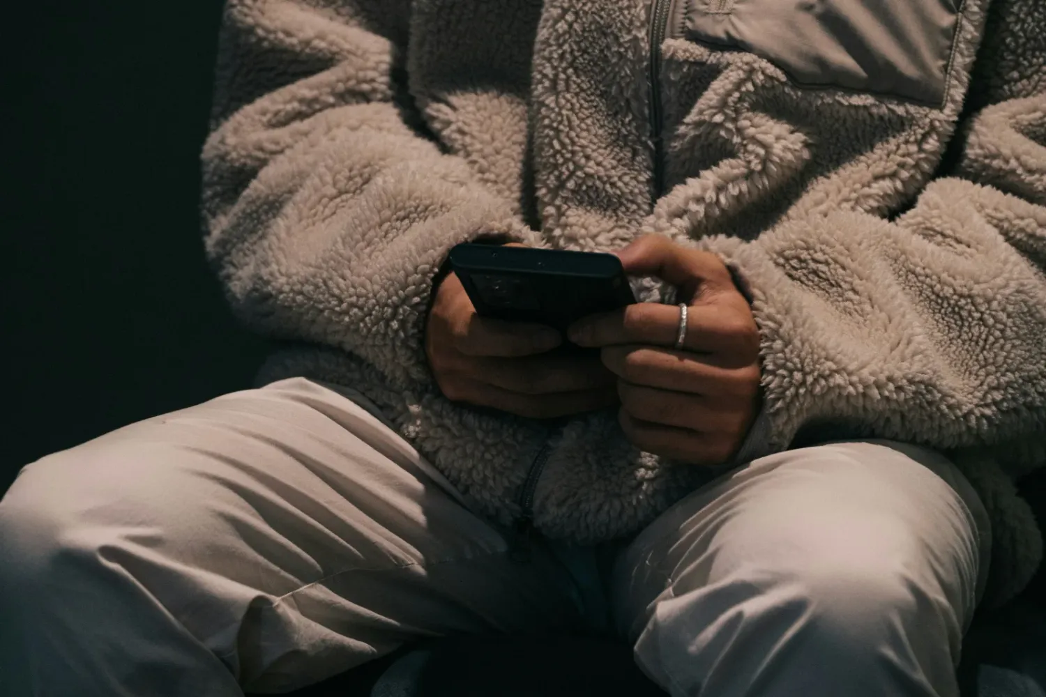 Female in wooly jacket texting on the phone